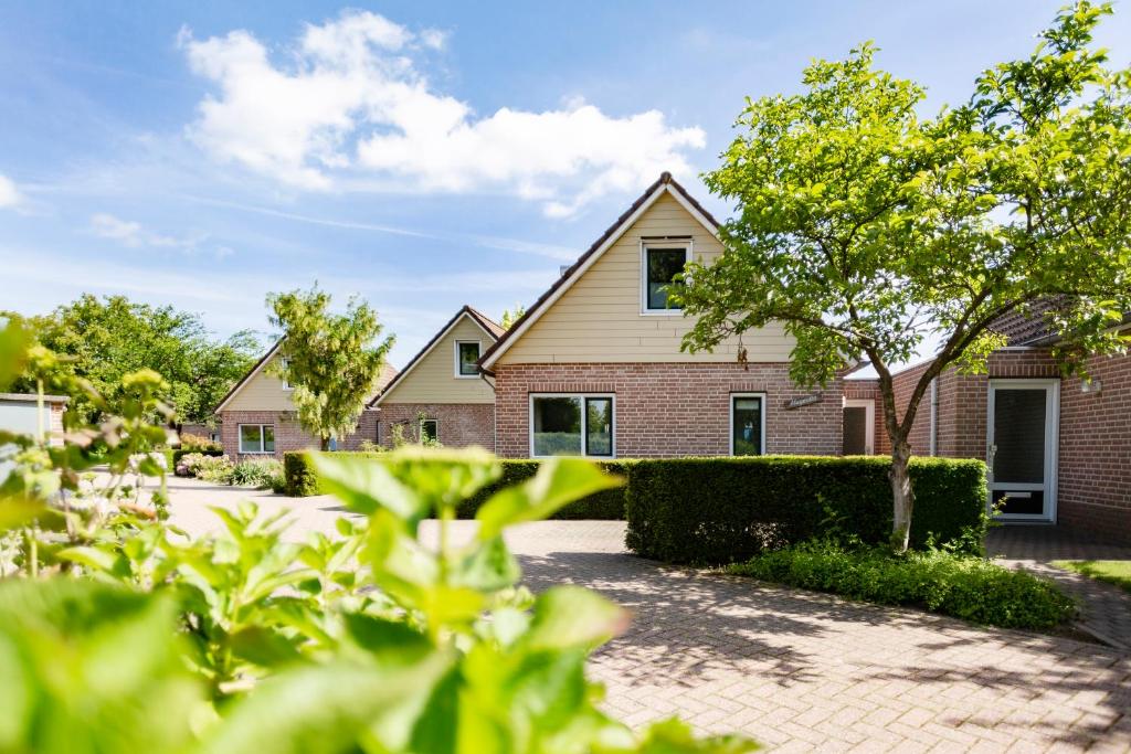 una casa de ladrillo con árboles delante de ella en Summio Bungalowpark De Riethorst, en Plasmolen