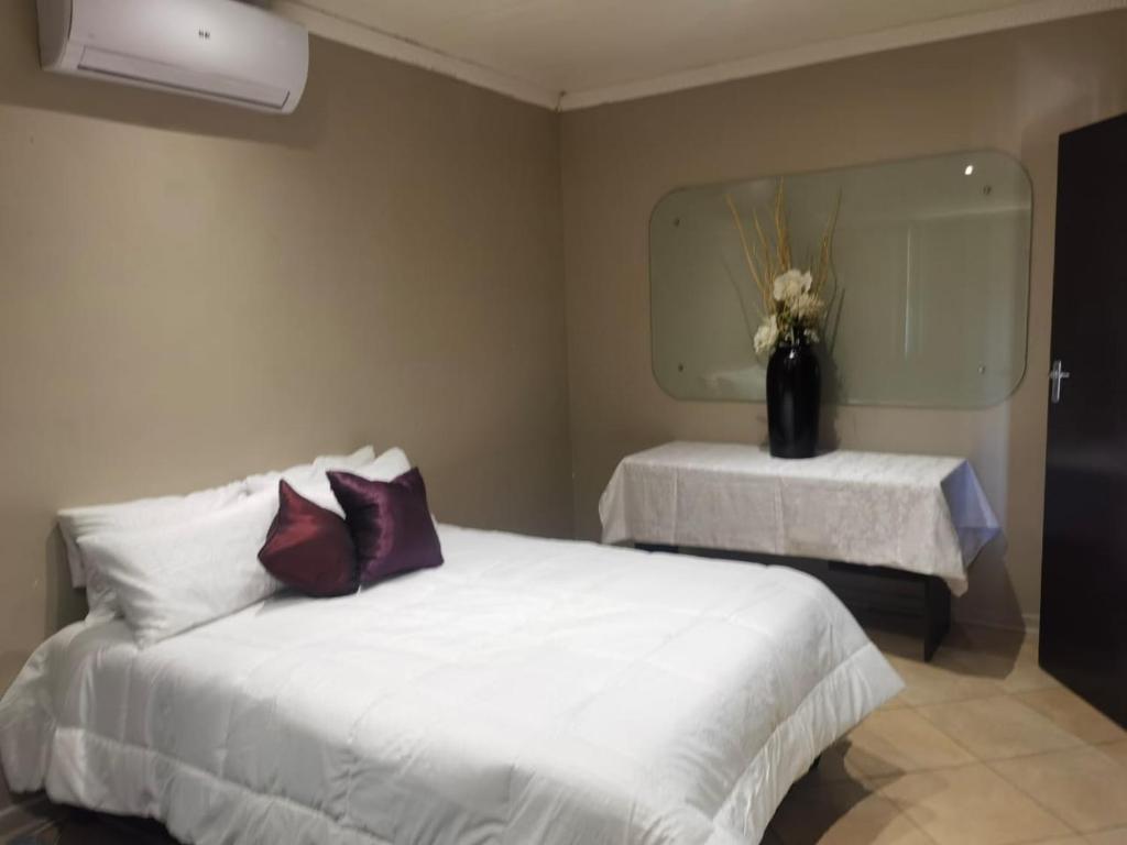 a bedroom with a white bed and a mirror at Mimosa's @ 44 in Roodepoort
