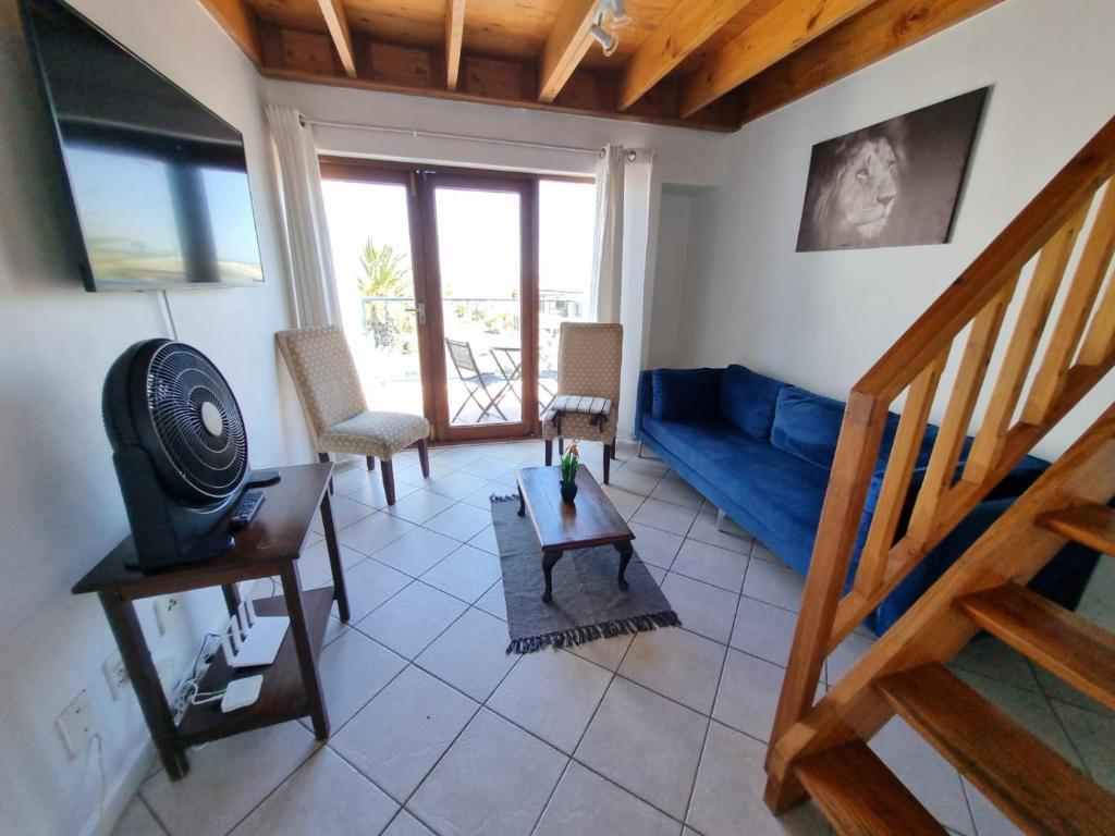 uma sala de estar com um sofá azul e uma mesa em 24 Arniston Village, Melkbosstrand em Melkbosstrand