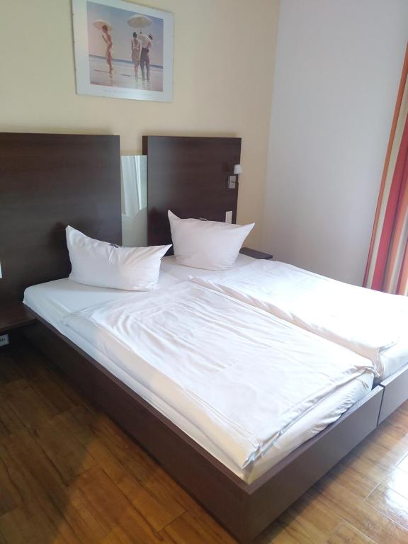 a large bed with white sheets and pillows at Hotel Auf der Bühn in Malsch