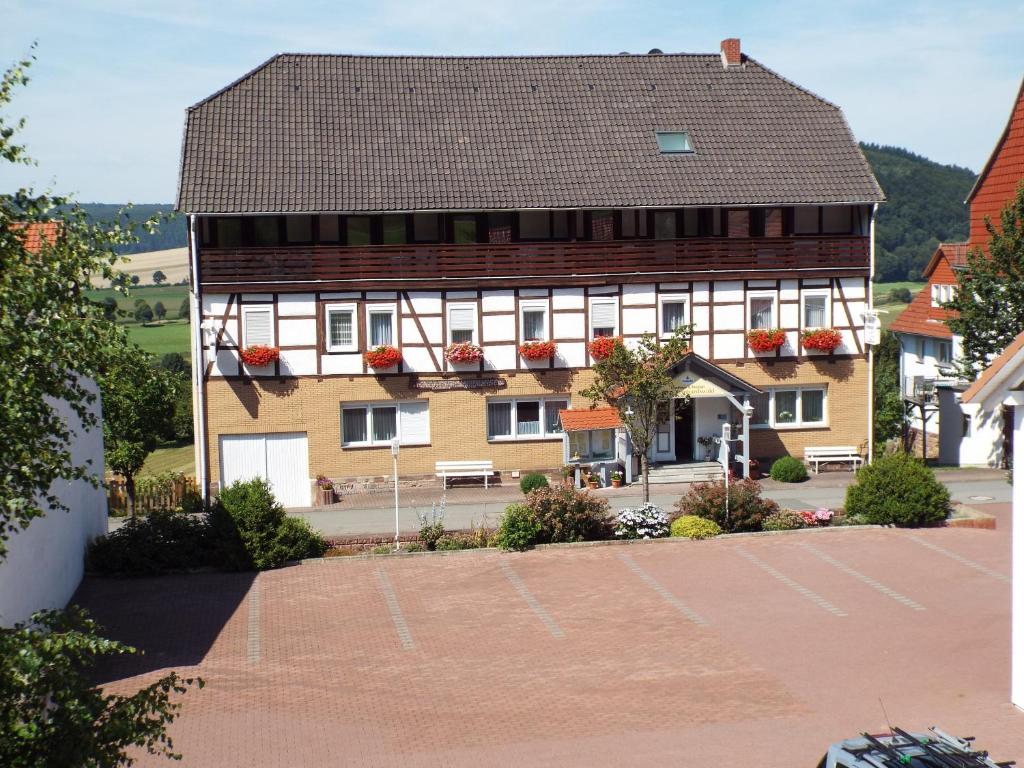 Hotel garni Zum Reinhardswald في Gewissenruh: مبنى كبير يوجد على جانبه علب الزهور