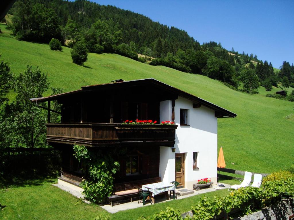 uma casa branca com uma varanda numa colina verde em Schoner Erika em Oberau