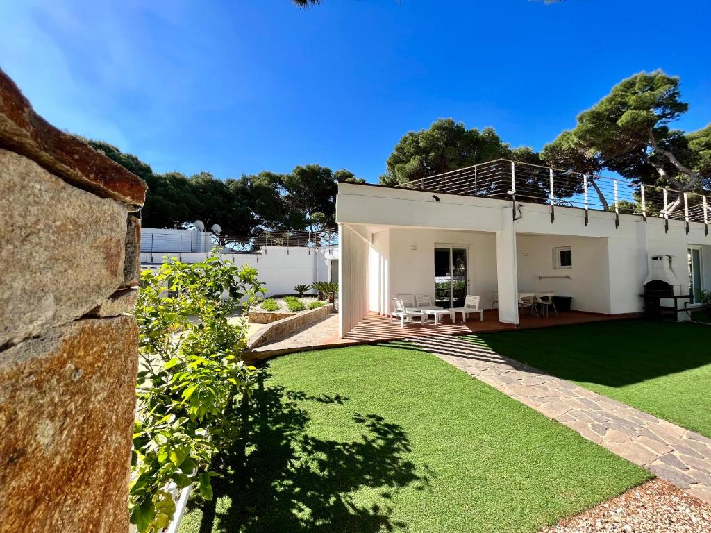 een huis met een grote tuin met groen gras bij Angolo Mare Apartments & Rooms in Porto Pino