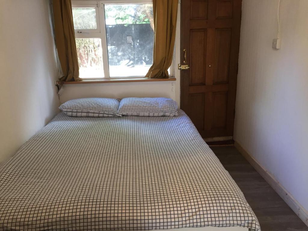 1 cama con 2 almohadas en una habitación con ventana en South Dublin Flat near Killiney Beach!, en Loughlinstown