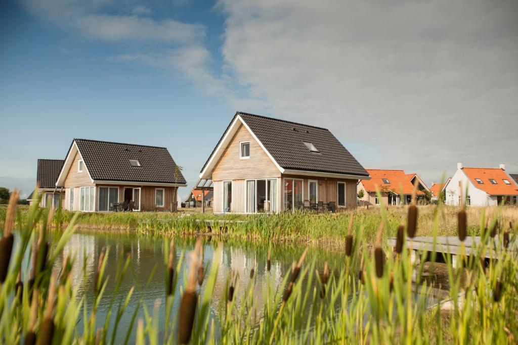 a couple of houses next to a body of water at Dormio Strand Resort Nieuwvliet-Bad in Nieuwvliet