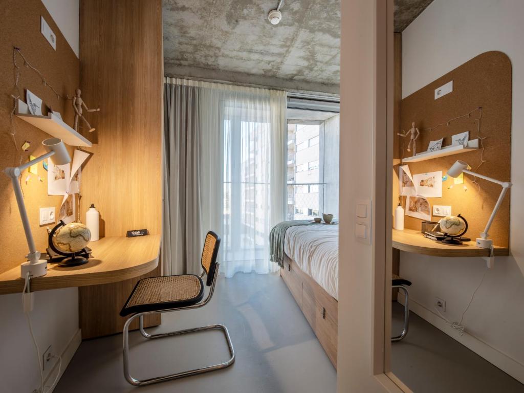 um quarto com uma cama, uma secretária e uma cadeira em micampus Porto Tower no Porto