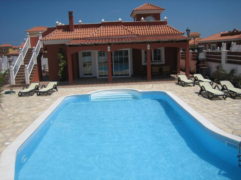 a large swimming pool in front of a house at Verano Brisa Private Golf Villa in Caleta De Fuste
