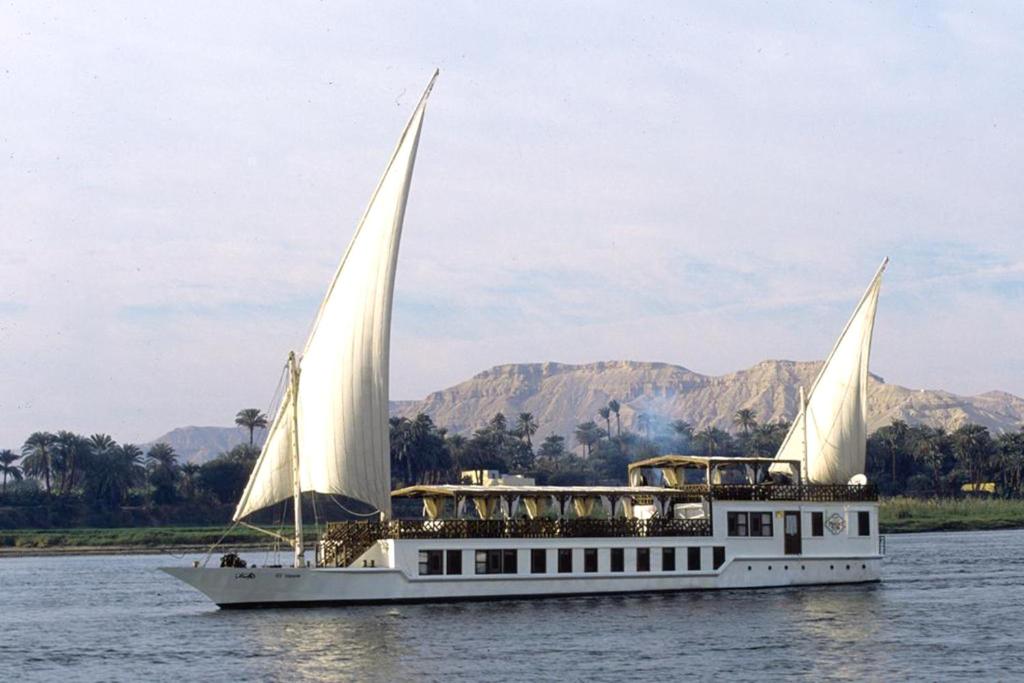 ein weißes Boot mit zwei Segeln im Wasser in der Unterkunft Farouz El Nil III Nile Cruise - Every Saturday from Luxor for 07 & 05 Nights in Luxor
