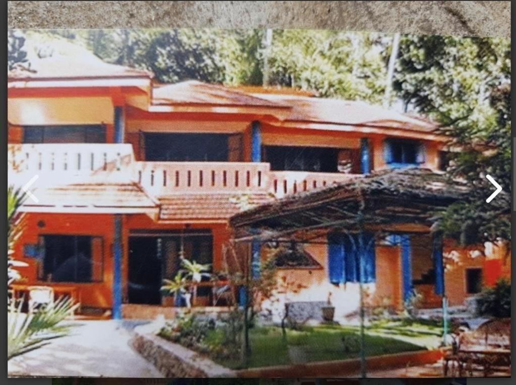 a large orange house with a yard in front of it at Neela House in Kovalam