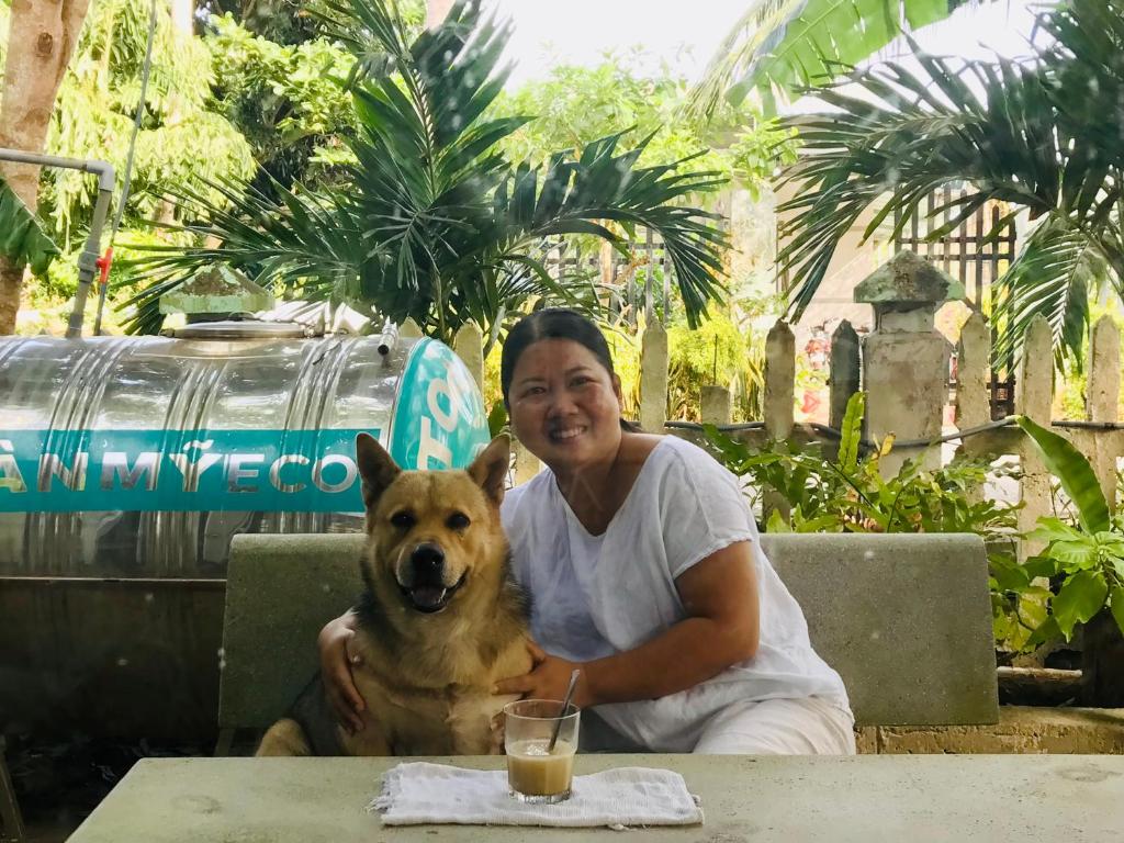 a woman sitting at a table with a dog at Eden House & Coffee Con Dao in Con Dao