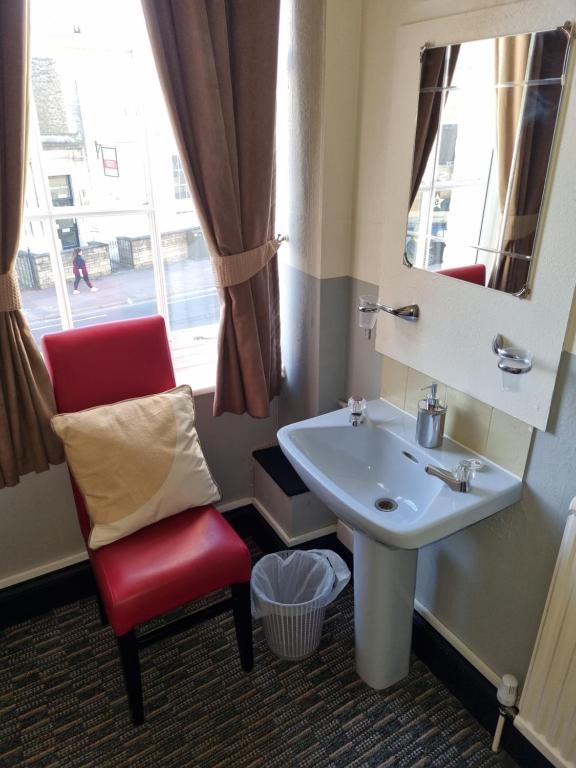 a bathroom with a red chair and a sink at Spalite Hotel in Gloucester
