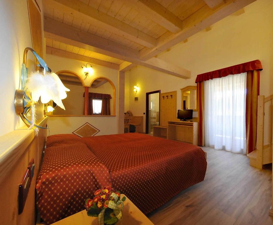 een slaapkamer met een rood bed in een kamer bij Albergo Alla Comparsa in Baselga di Pinè
