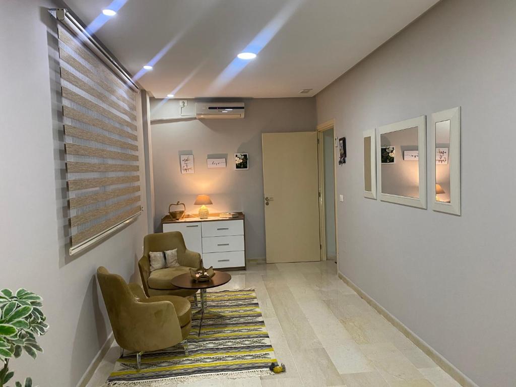 Habitación con 2 sillas, mesa y escritorio. en Superbe appartement hautstanding en Sfax