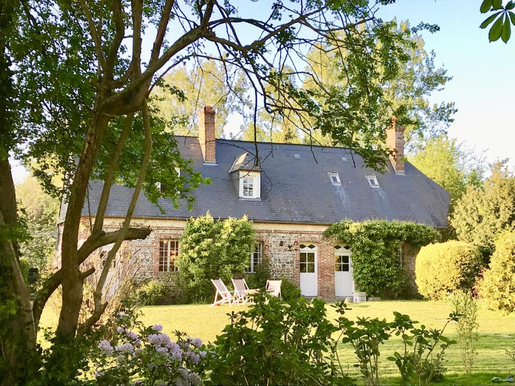 une maison en pierre avec deux chaises devant elle dans l'établissement Vieux Logis, à Varengeville-sur-Mer
