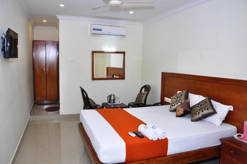 a bedroom with a large bed with a wooden headboard at HOTEL NNP GRAND Rameswaram in Rāmeswaram