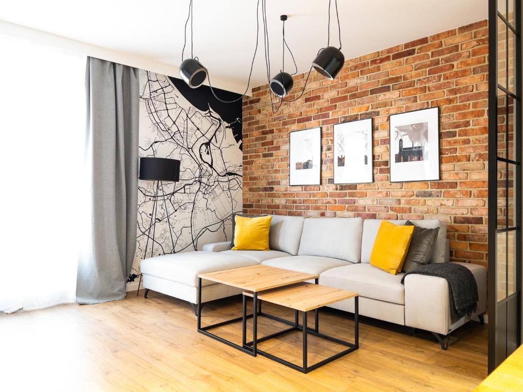 een woonkamer met een witte bank en een bakstenen muur bij Mint Apartments Gdańsk DOKI in Gdańsk
