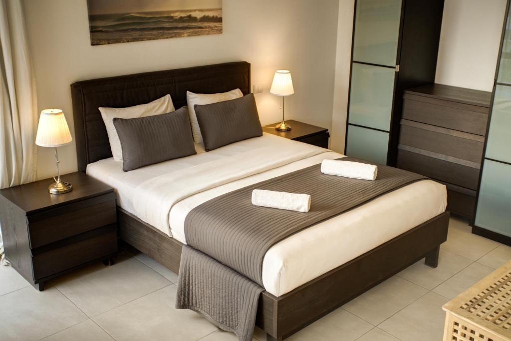 a bedroom with a large bed with two night stands at Shoreline Apartment - Tala Bay in Aqaba