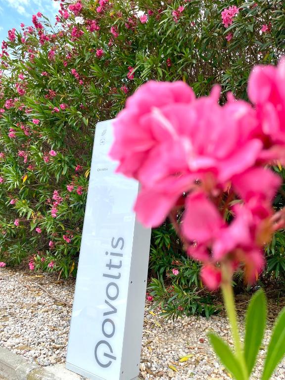 a sign sitting next to a pink flower at Premiere Classe Perpignan Sud in Perpignan