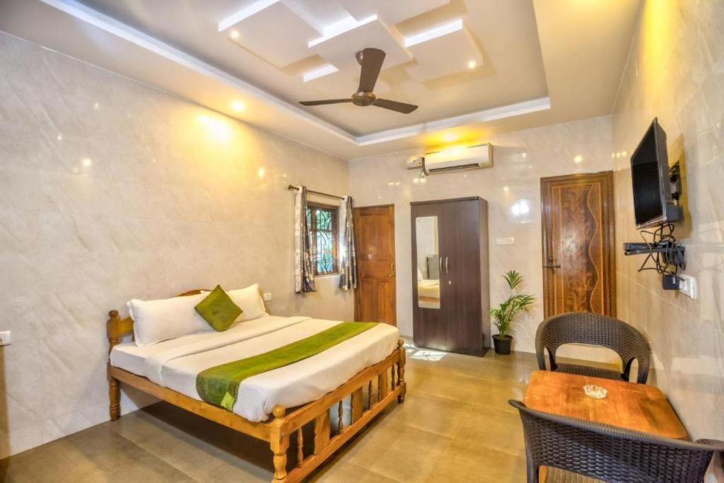 a bedroom with a bed and a table and a tv at Calangute Beach Steps in Calangute