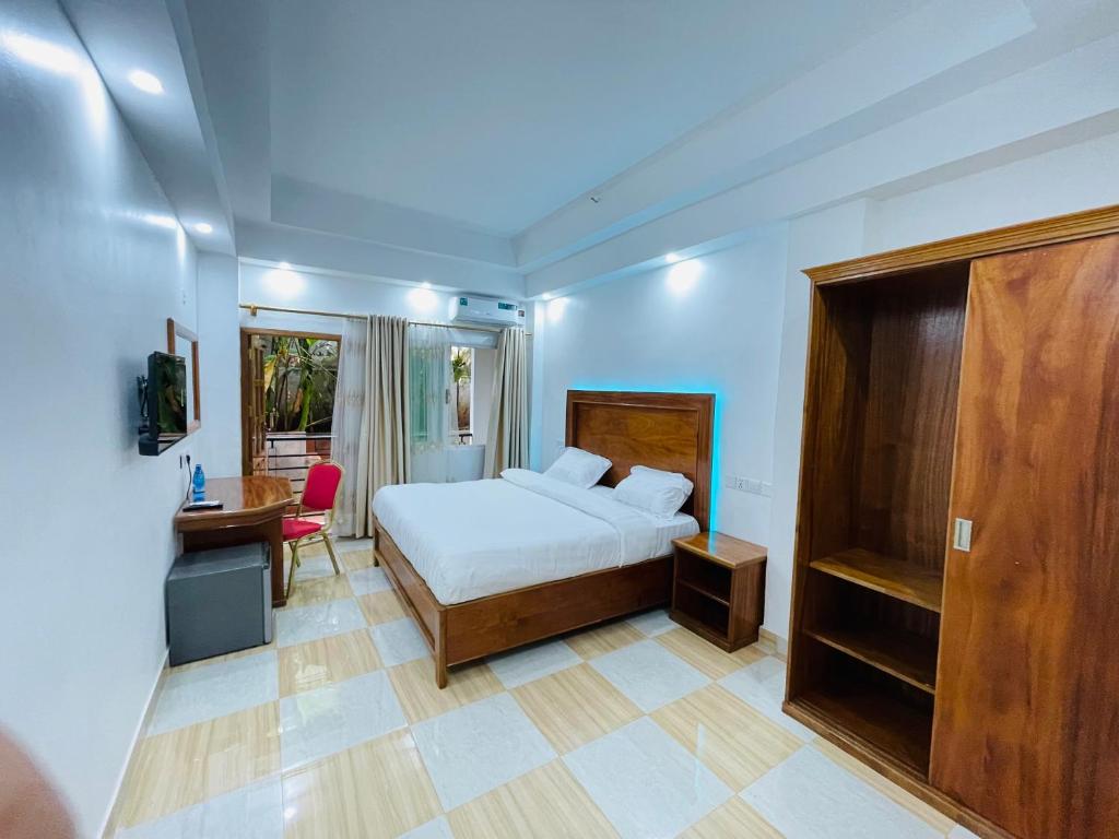 a bedroom with a bed and a desk and a table at Pulickal Heights Hotel in Entebbe