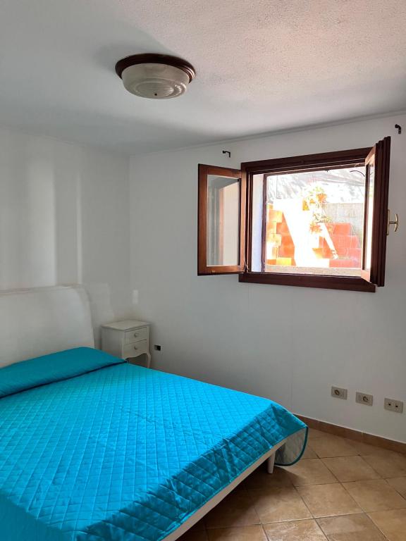 a bedroom with a blue bed and a window at Casa Vacanze Padru in Padru