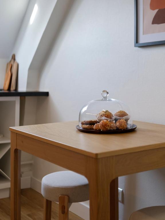 a table with a plate of donuts in a glass dome at Calme, Confort et Propreté in Vittel