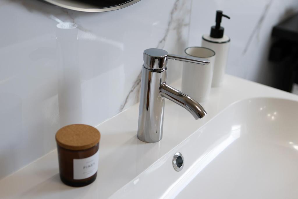 a bathroom sink with a faucet and a jar at Calme, Confort et Propreté in Vittel