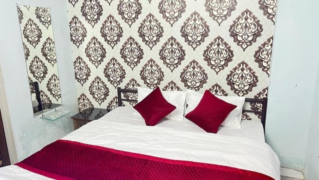 a white bed with red pillows in a bedroom at Hotel Vrindavan Ratnagiri in Ratnagiri