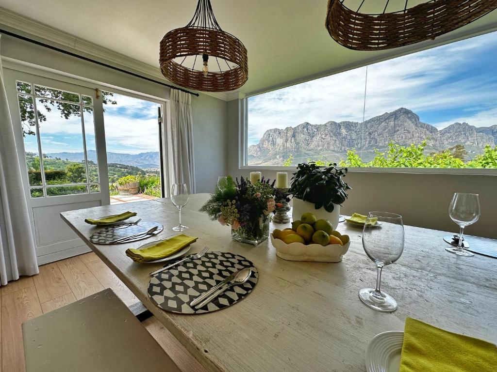 - une salle à manger avec une table et une vue sur les montagnes dans l'établissement Camberley Wines - Luxury Accommodation, à Stellenbosch