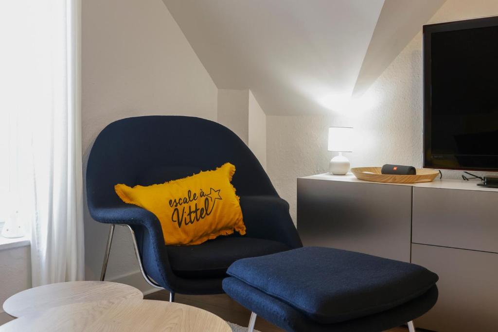 a blue chair with a yellow pillow in a room at Calme, Confort et Propreté in Vittel