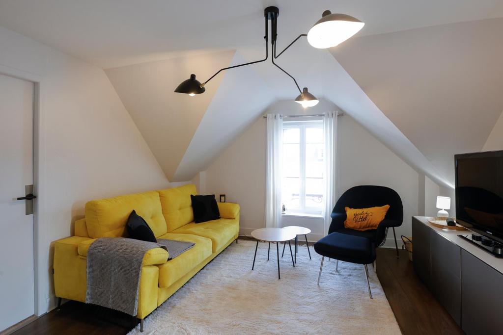 a living room with a yellow couch and two chairs at Calme, Confort et Propreté in Vittel