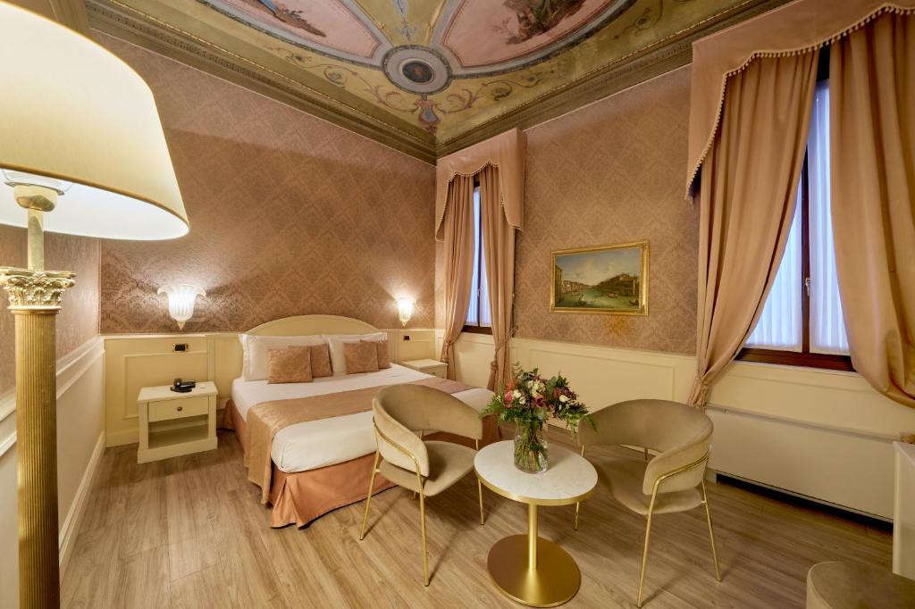 una camera d'albergo con letto, tavolo e sedie di Duodo Palace a Venezia
