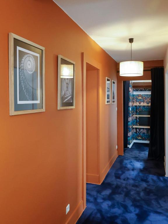 an orange hallway with two pictures on the wall at Calme, Confort et Propreté in Vittel