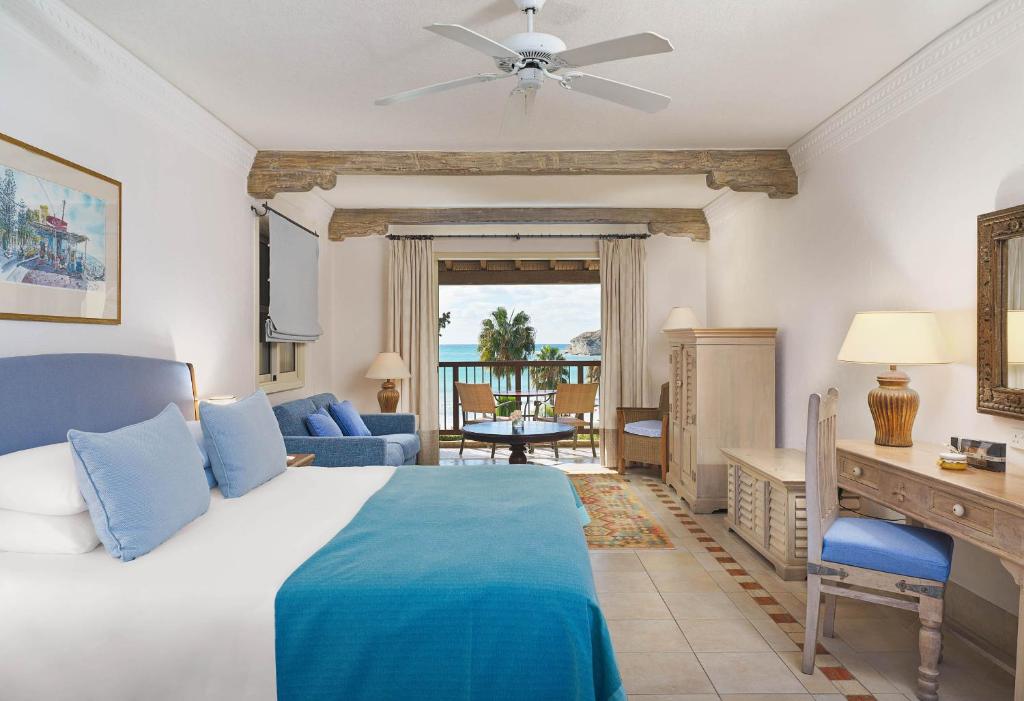 a bedroom with a bed and a desk and a couch at Columbia Beach Resort in Pissouri