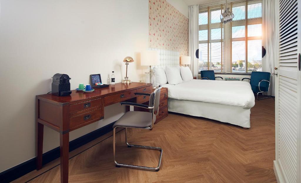 a bedroom with a desk and a bed and a bed and a desk at Hotel New York by WestCord in Rotterdam