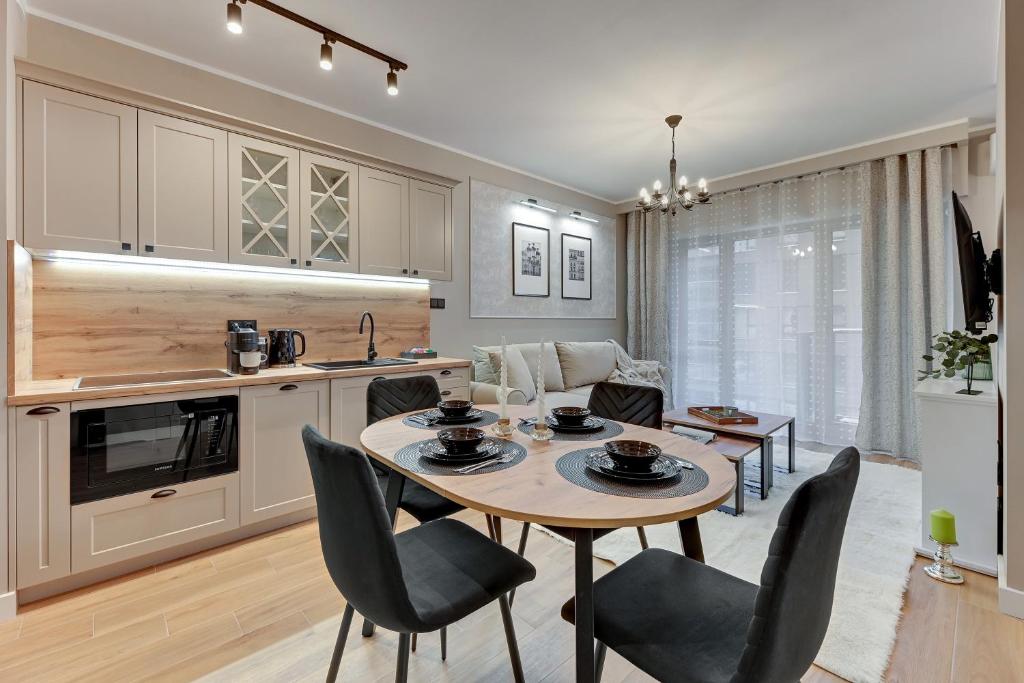 a kitchen and living room with a table and chairs at Downtown Apartments Nadmotławie Estate Gym, Sauna & Parking in Gdańsk