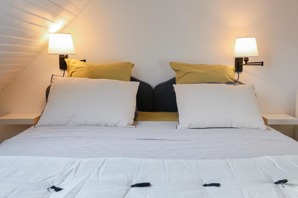 a bed with white sheets and yellow pillows in a room at Calme, Confort et Propreté in Vittel