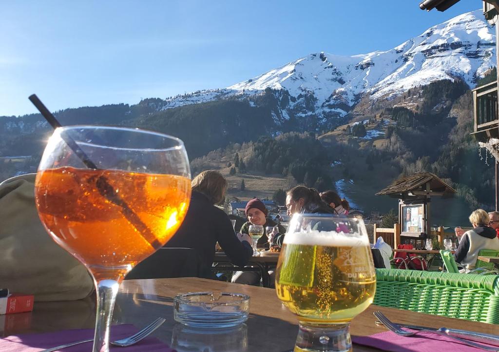 deux verres de bière assis sur une table avec une montagne dans l'établissement SKI AUX PIEDS et PIEDS DANS L'EAU, aux Contamines-Montjoie
