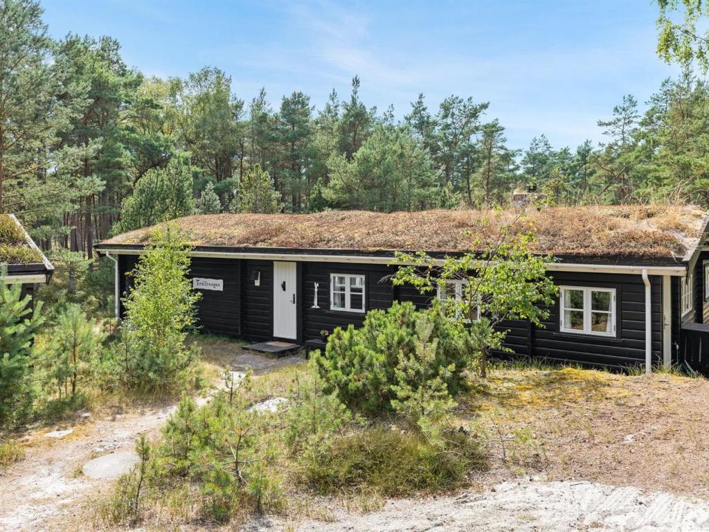 uma pequena casa preta com telhado de relva em Holiday Home Solfred - 200m from the sea in Bornholm by Interhome em Vester Sømarken