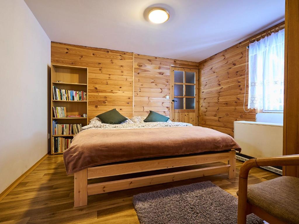 a bedroom with a bed with a wooden wall at Holiday Home Chaloupka U lesa by Interhome in Harrachov