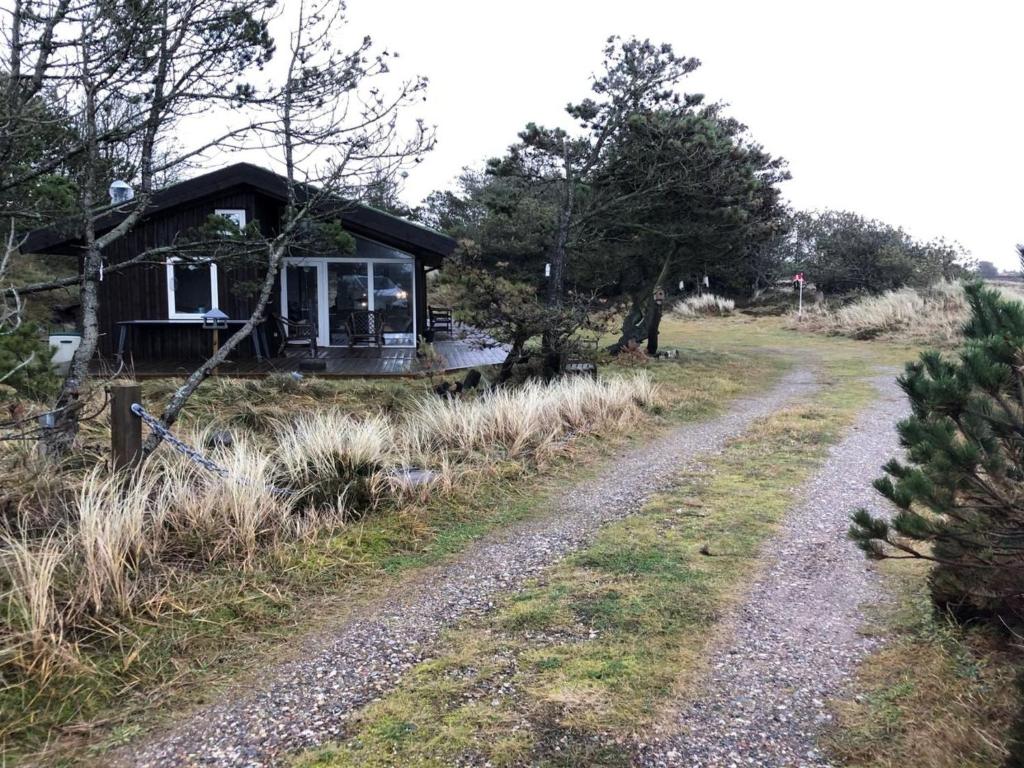a gravel road leading to a cabin in the woods at Holiday Home Lagho - 500m from the sea in NW Jutland by Interhome in Pandrup