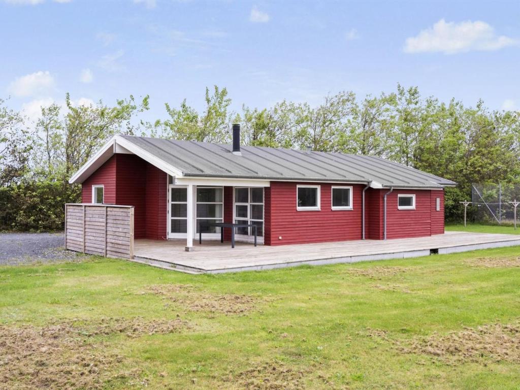 een klein rood huis met een grote veranda bij Holiday Home Rudy - 800m from the sea in NW Jutland by Interhome in Løkken