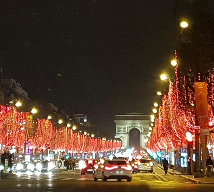 a city street lined with christmas lights at night at Au pied de la tour Eiffel Trocadéro in Paris