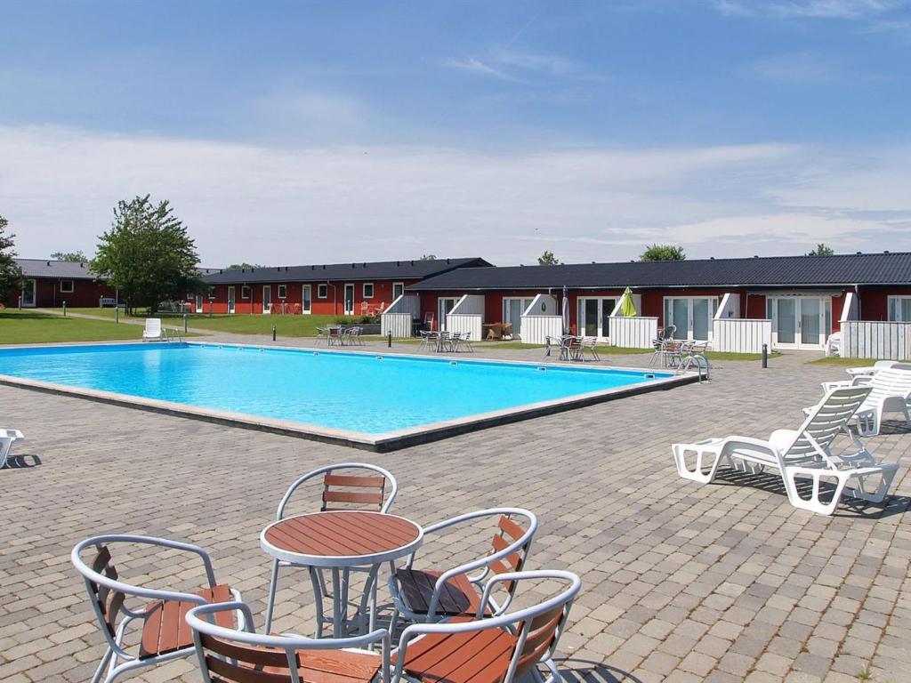 a swimming pool with chairs and a table and a table and chairs at Holiday Home Thorulf - 6km from the sea in Bornholm by Interhome in Åkirkeby