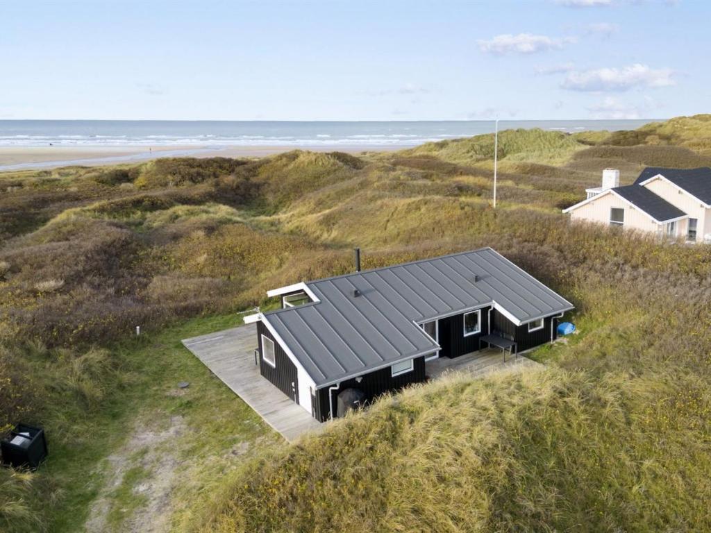 een uitzicht over een zwart huis op een strand bij Holiday Home Mirla - 50m from the sea in NW Jutland by Interhome in Saltum