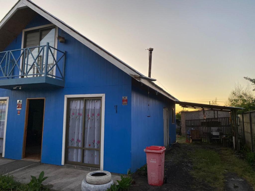 ein blaues Haus mit einem roten Mülleimer davor in der Unterkunft casa familiar in Guangualí