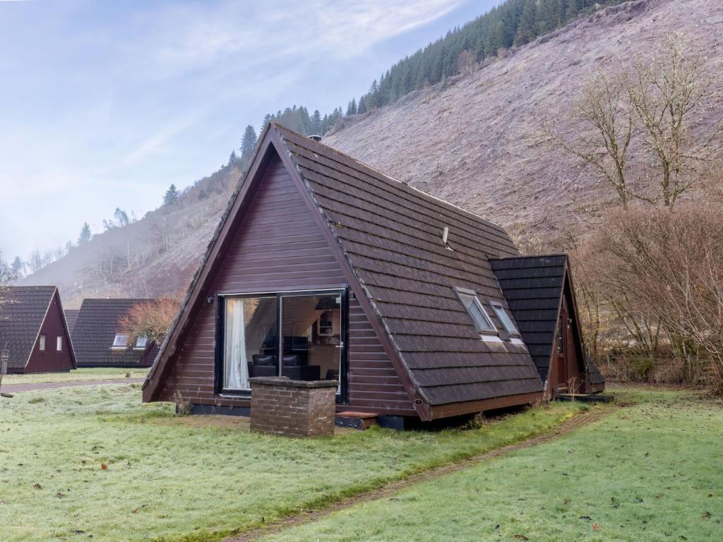 a small house with a brown roof in a field at Chalet Caledonia Lodge by Interhome in Spean Bridge