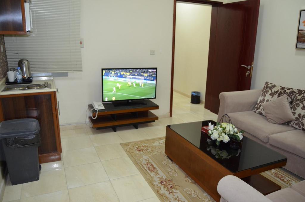 a living room with a tv and a couch and a table at اجنحة العنوان للشقق المخدومة in Al Jubayl