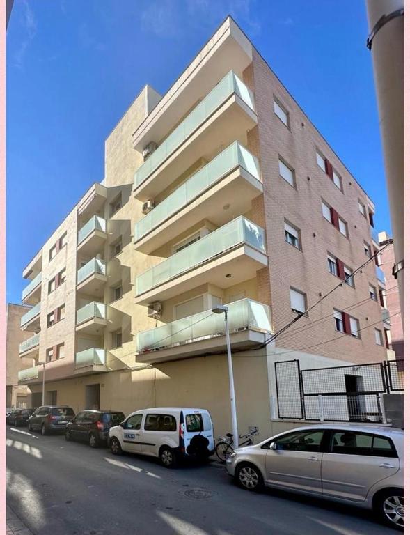 un gran edificio con coches estacionados frente a él en VILLAMAGNA PUEBLO OROPESA en Oropesa del Mar