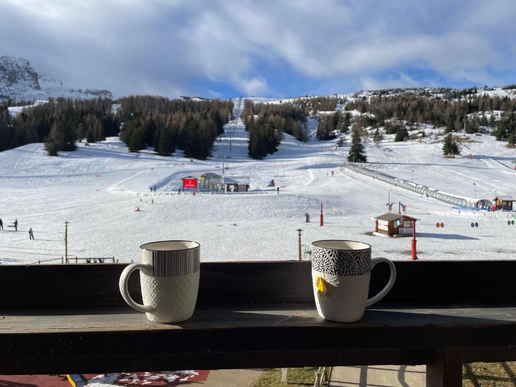 two coffee cups sitting on a window sill with a ski slope at Le Vert Montagne Studio lumineux plein sud in Le Dévoluy